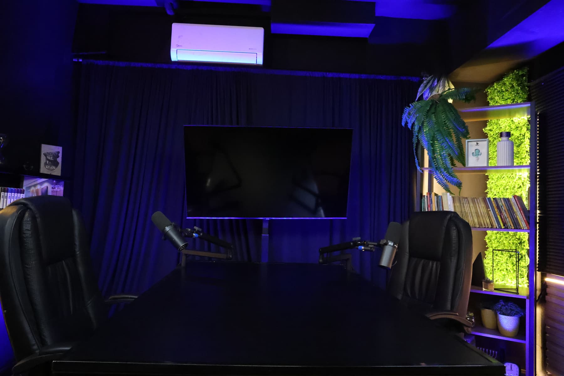 Set de podcast da POCT com mesa preta, poltronas de couro e iluminação azul